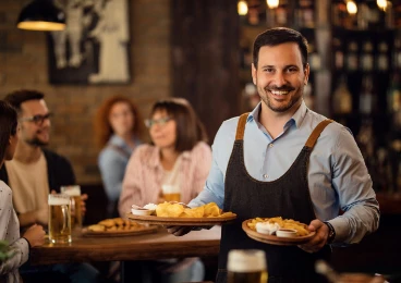 camarero feliz-sosteniendo platos comida mirando camara mientras atiende invitados restaurante