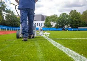 trabajador marcando limites de un estadio de futbol